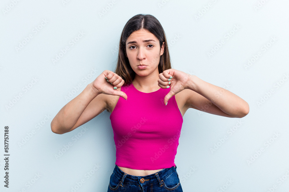 Young caucasian woman isolated on blue background showing a dislike gesture, thumbs down. Disagreement concept. Young caucasian woman isolated on blue background showing a dislike gesture, thumbs down. Disagreement concept.