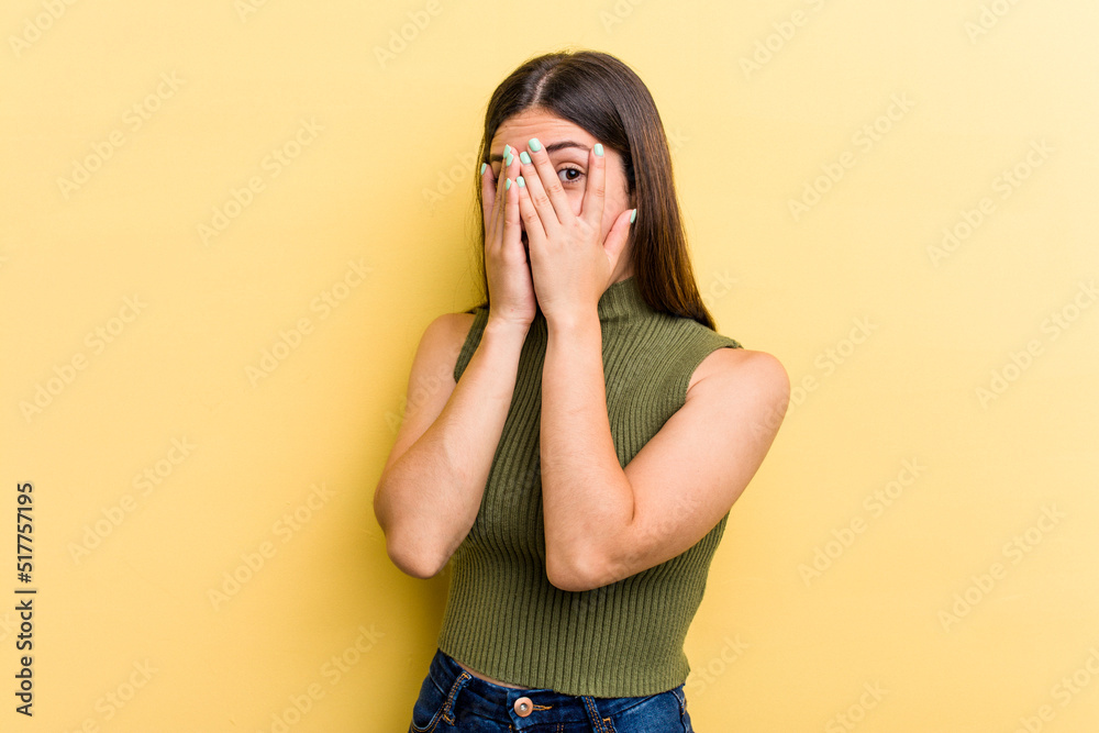 Young caucasian woman isolated on yellow background blink through fingers frightened and nervous. Young caucasian woman isolated on yellow background blink through fingers frightened and nervous.