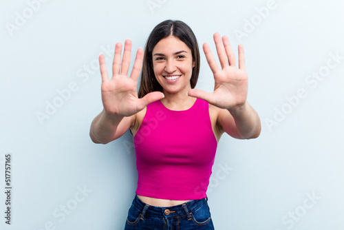 Young caucasian woman isolated on blue background showing number ten with hands.