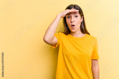 Young caucasian woman isolated on yellow background looking far away keeping hand on forehead. © Asier