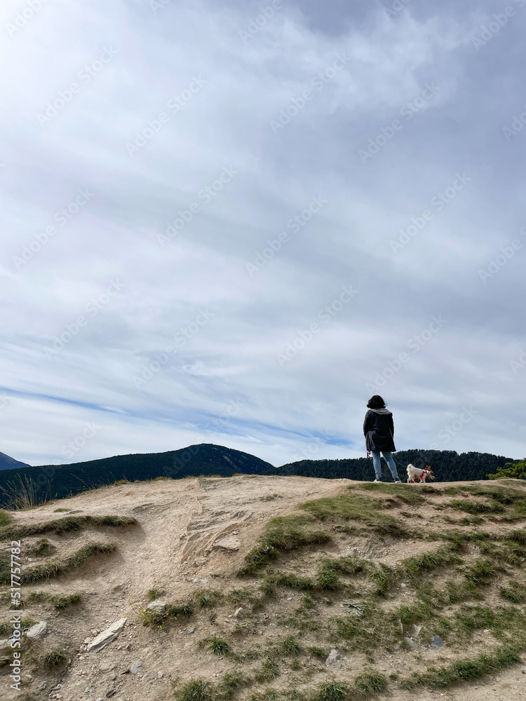 Woman observes the mountain landscape, with her dogs. Motivational concept.