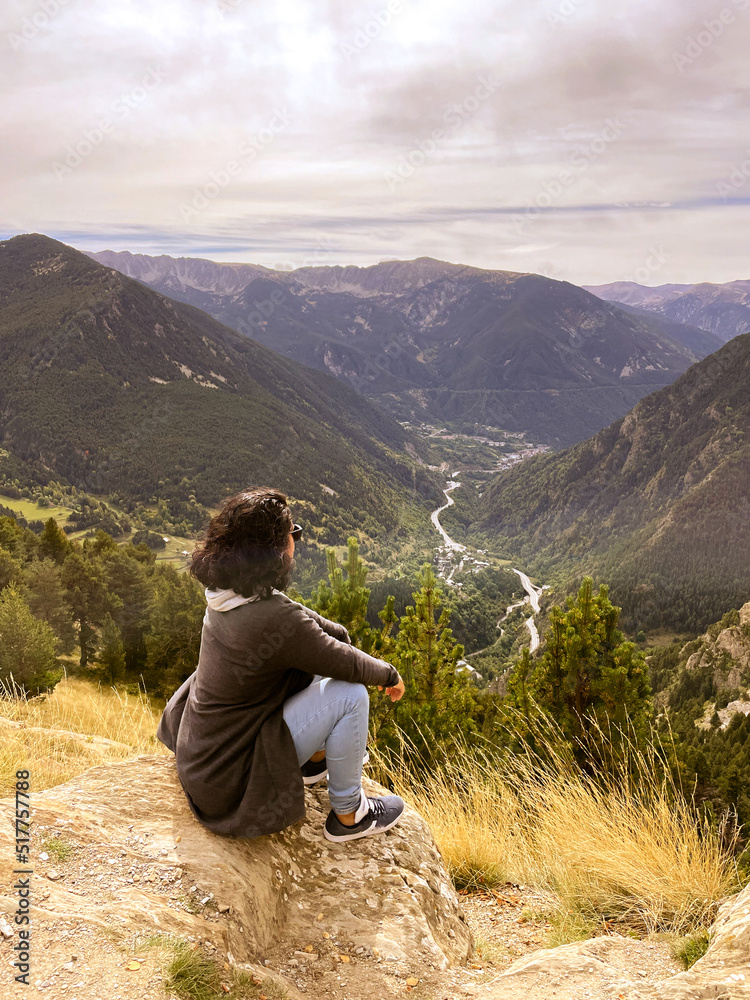 Woman sitting on top of a mountain observing the landscape. Motivational concept. Woman sitting on top of a mountain observing the landscape. Motivational concept.