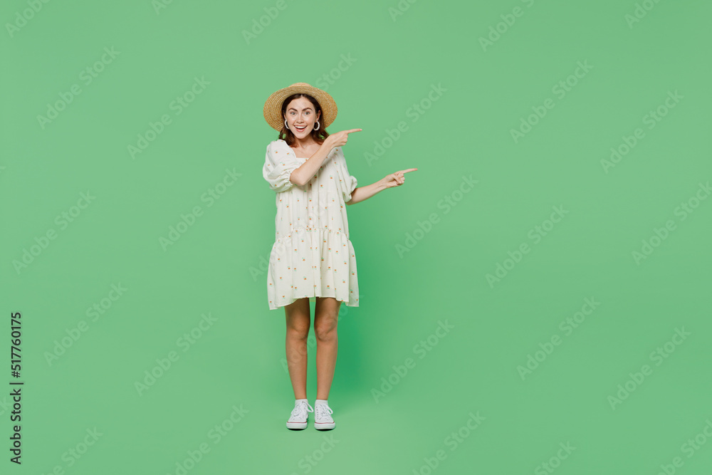 Full body young happy smiling woman she 20s wears white dress hat sit in bag chair point index finger aside on workspace area isolated on plain pastel light green background. People lifestyle concept. Full body young happy smiling woman she 20s wears white dress hat sit in bag chair point index finger aside on workspace area isolated on plain pastel light green background. People lifestyle concept.