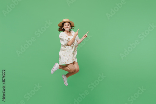 Full body young happy smiling overjoyed excited woman she 20s in white dress hat jump high point index finger aside on workspace area isolated on plain pastel light green background studio portrait.