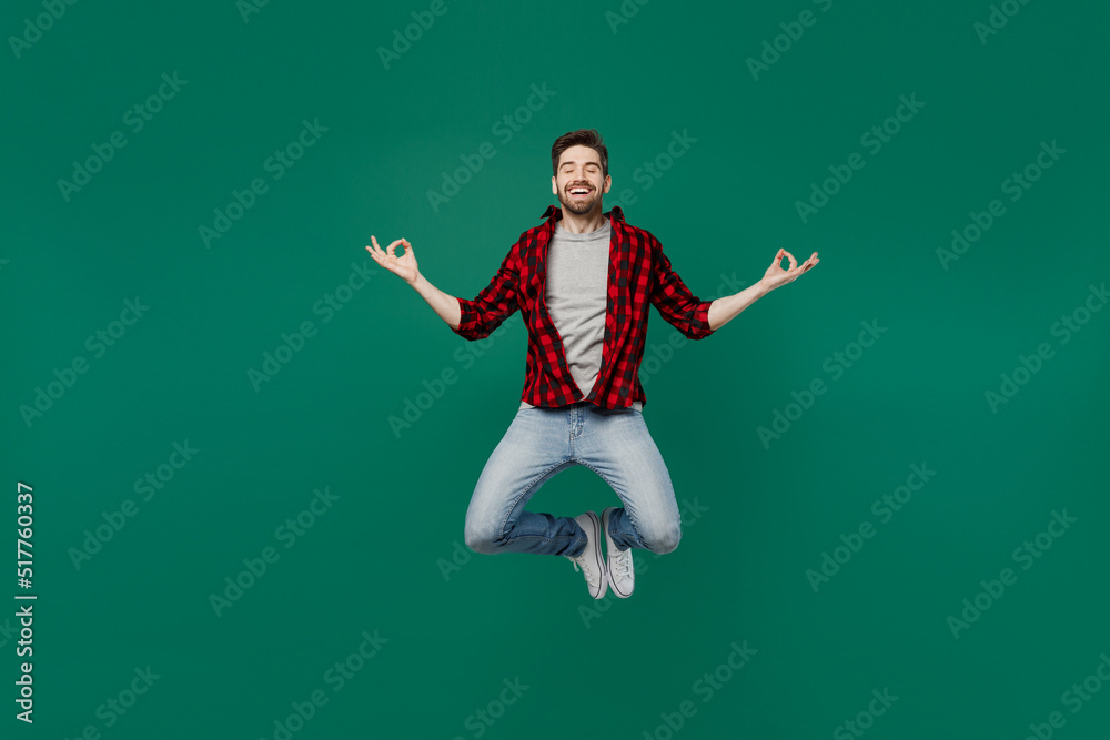 Full body young happy smiling caucasian man he 20s in red shirt grey t-shirt hold spreading hands in yoga om aum gesture relax meditate try to calm down isolated on plain dark green background studio.