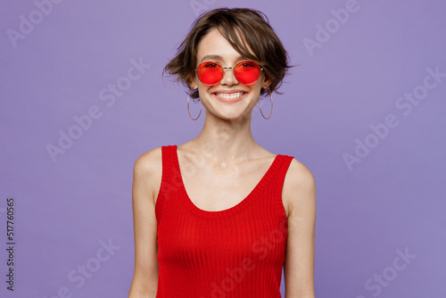 Young smiling happy cheerful fun cool caucasian european woman 20s she wearing red tank shirt eyeglasses look camera isolated on plain purple color backround studio portrait. People lifestyle concept.