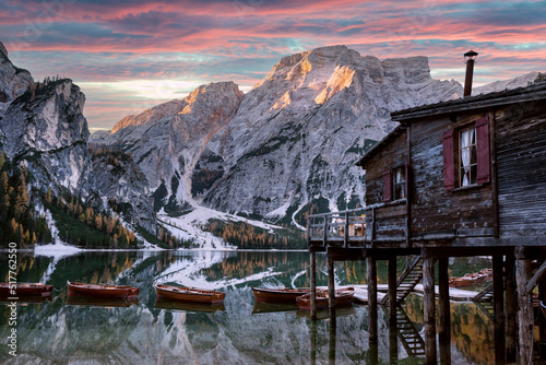 Picturesque landscape with famous lake Braies in autumn Dolomites mountains. Wooden boats and pier in clear water of Lago di Braies, Dolomite Alps, Italy. Seekofel mountain peak on background