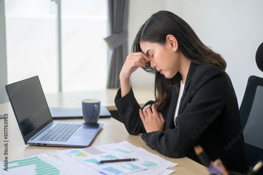 Stressed young business woman working on laptop with documents in modern office, workload concept Stressed young business woman working on laptop with documents in modern office, workload concept