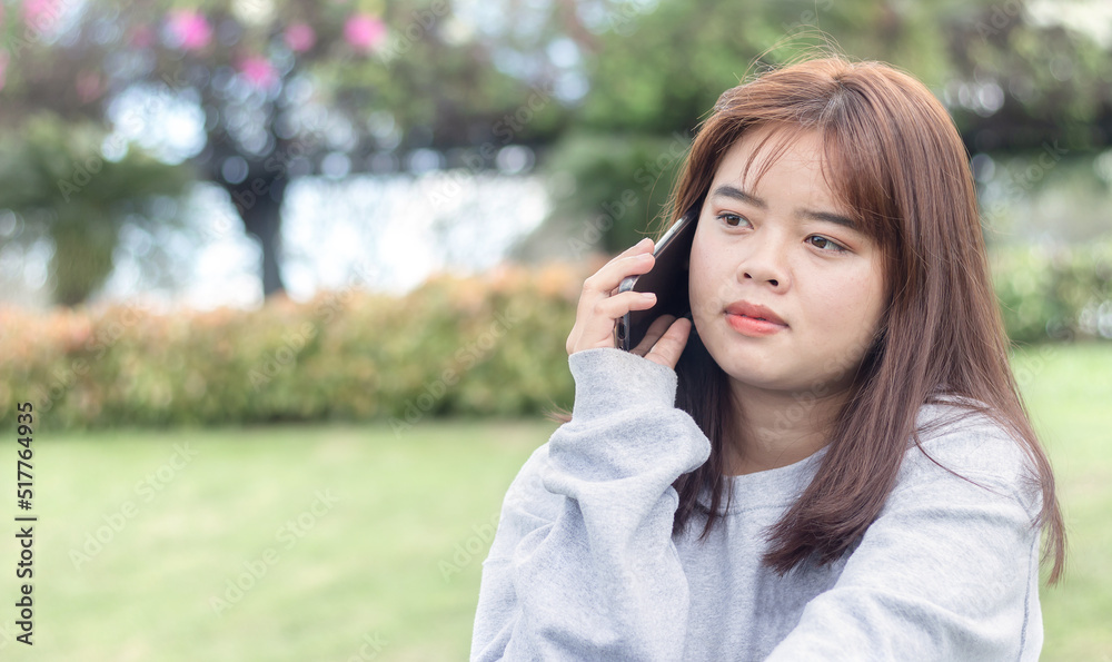 Portrait of an Asian teenage girl using a mobile phone in the garden Portrait of an Asian teenage girl using a mobile phone in the garden
