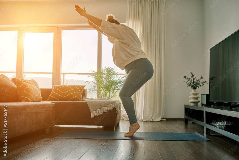 Woman doing online yoga at home. Female trener teaches asana in video conference. Health care, authenticity, sense of balance and calmness.
 - obrazy, fototapety, plakaty 