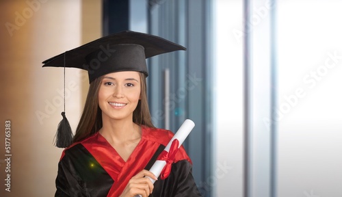 Happy university student in graduation gown and cap holding diploma certificate.