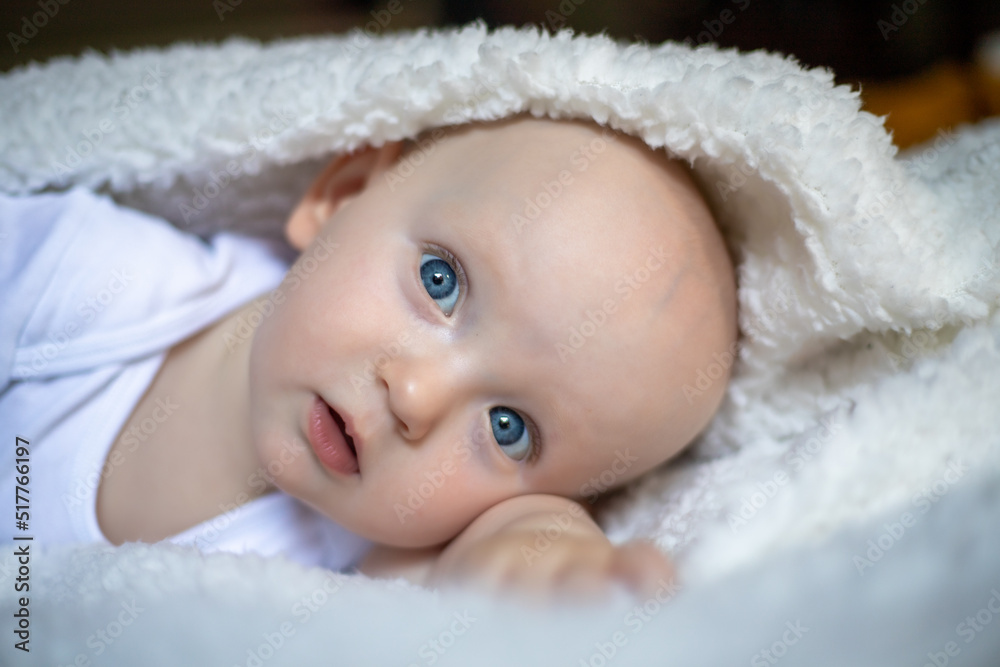 smiling baby looking at camera under a white blanket, towel. selective focus smiling baby looking at camera under a white blanket, towel. selective focus