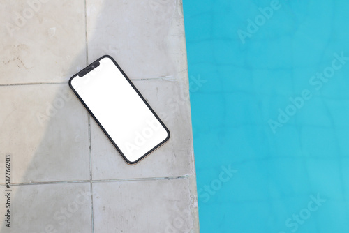 Mockup of a blank white screen smartphone close to a pool