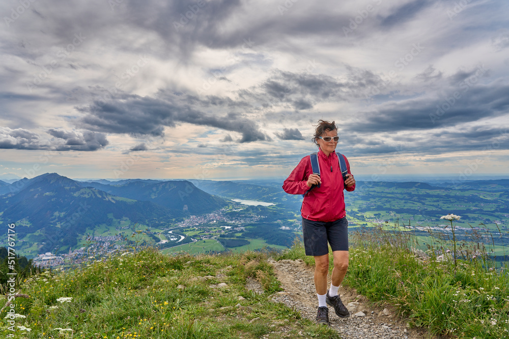 nice senior woman hiking at Mount Gruenten in the Allgaeu Alps with awesomw view over Iller valley to Lake Alpsee and Lake of Constanz, Bodensee, Bavaria, Germany nice senior woman hiking at Mount Gruenten in the Allgaeu Alps with awesomw view over Iller valley to Lake Alpsee and Lake of Constanz, Bodensee, Bavaria, Germany