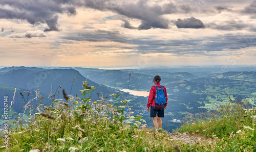 nice senior woman hiking at Mount Gruenten in the Allgaeu Alps with awesomw view over Iller valley to Lake Alpsee and Lake of Constanz, Bodensee, Bavaria, Germany
