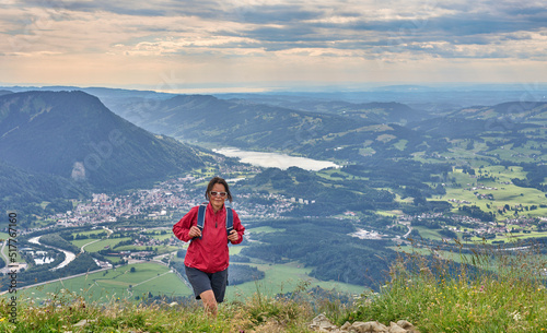 nice senior woman hiking at Mount Gruenten in the Allgaeu Alps with awesomw view over Iller valley to Lake Alpsee and Lake of Constanz, Bodensee, Bavaria, Germany