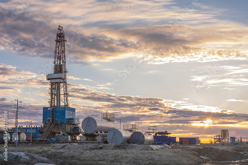 Infrastructure and equipment for drilling wells and oil and gas production. In the background there is a beautiful sky in the rays of the setting sun photo