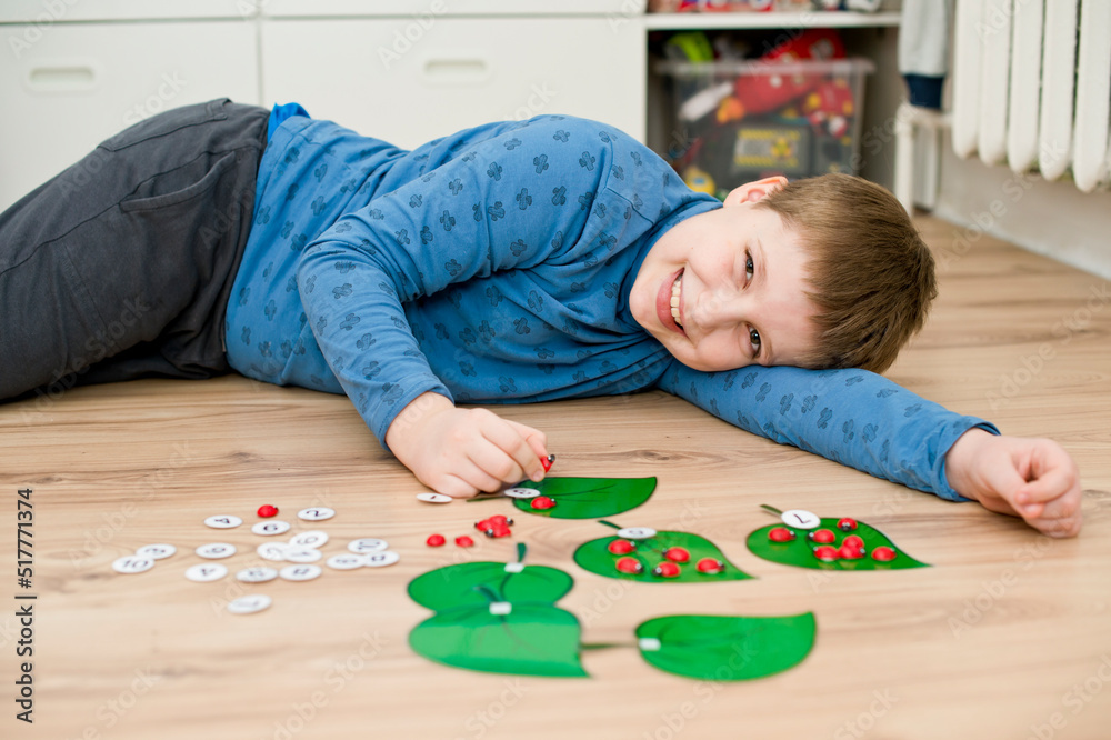 Boy lying on the floor and playing homemade counting game Boy lying on the floor and playing homemade counting game