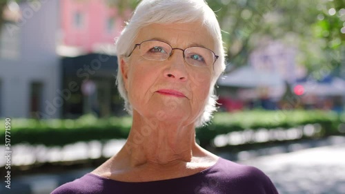 Serious old woman with glasses outside. Portrait of grey haired female with grumpy and skeptical look on face. A conservative and judgemental republican that is disapproving and unhappy photo
