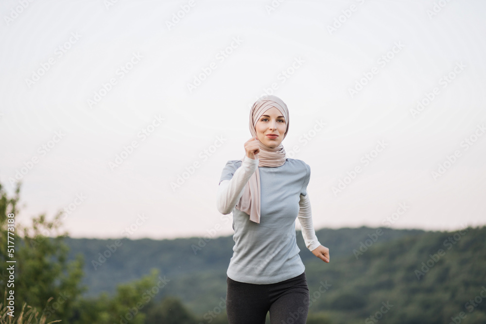Jogging Arabic woman in hijab running in green park on beautiful summer day. Sport fitness model Muslim ethnicity training outdoor for marathon. Jogging Arabic woman in hijab running in green park on beautiful summer day. Sport fitness model Muslim ethnicity training outdoor for marathon.
