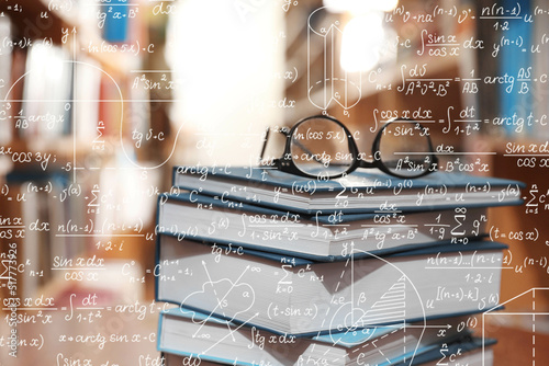 Science and education concept. Illustration of basic physics and mathematics formulas and stack of books with glasses in library photo