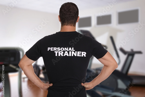 Fototapete Professional personal trainer in gym, back view
