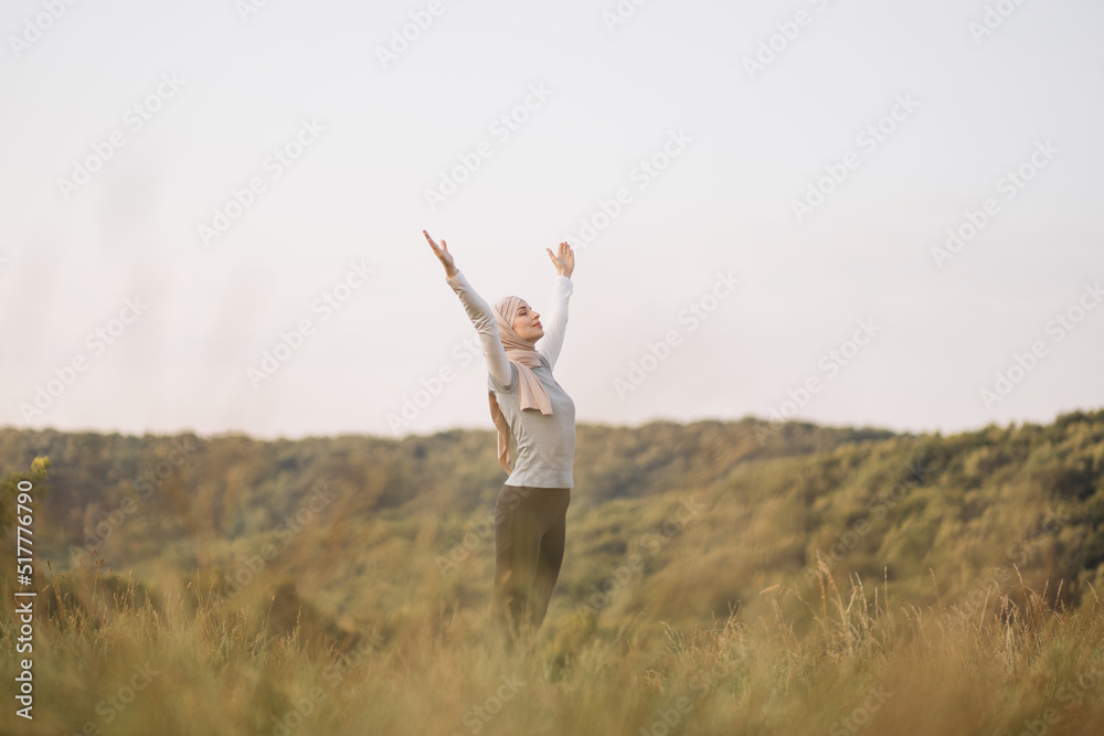 Back view of muslim woman enjoying the background of summer morning park and feeling free with the wind and sky after jogging, health and sport concept. Back view of muslim woman enjoying the background of summer morning park and feeling free with the wind and sky after jogging, health and sport concept.