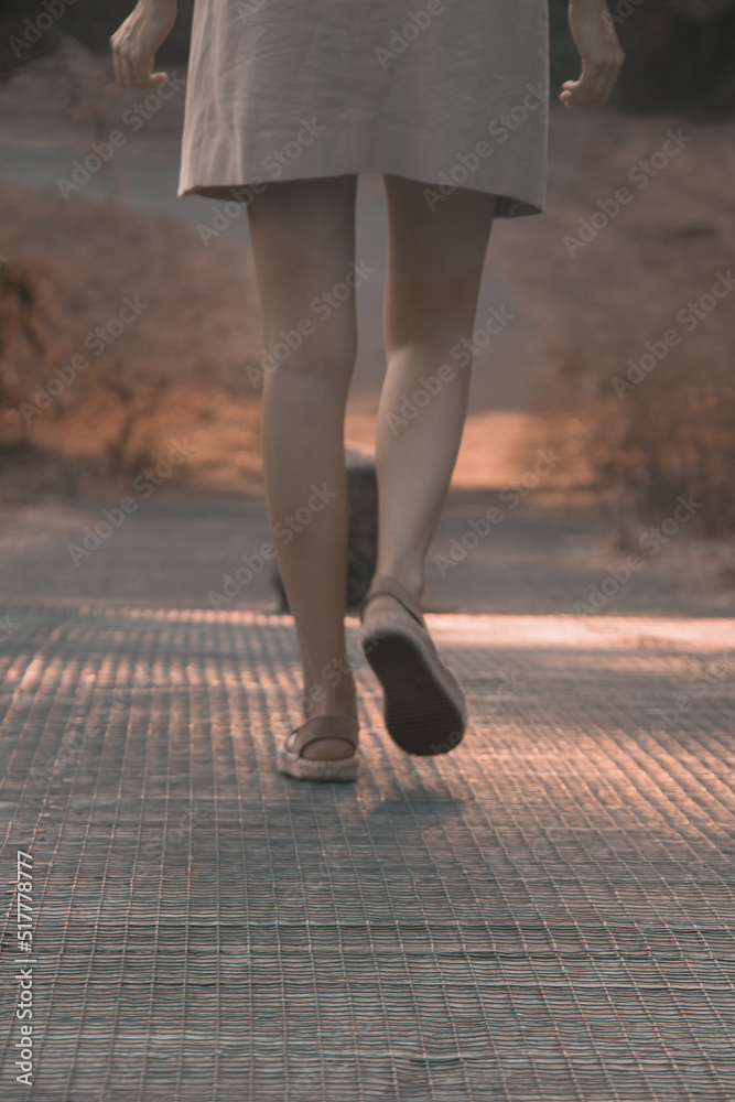 close-up of a girl strolling along a wooden bridge. Tranquility at sunset.