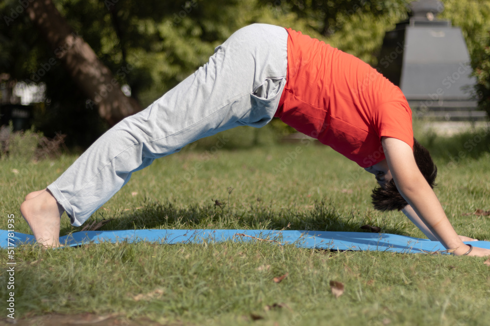 Yoga Kid, Young boy Practicing Yoga Outdoors in the park in Morning, healthy lifestyle concept