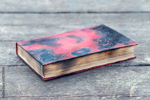 A charred closed book on an old wooden table. The book after the fire photo