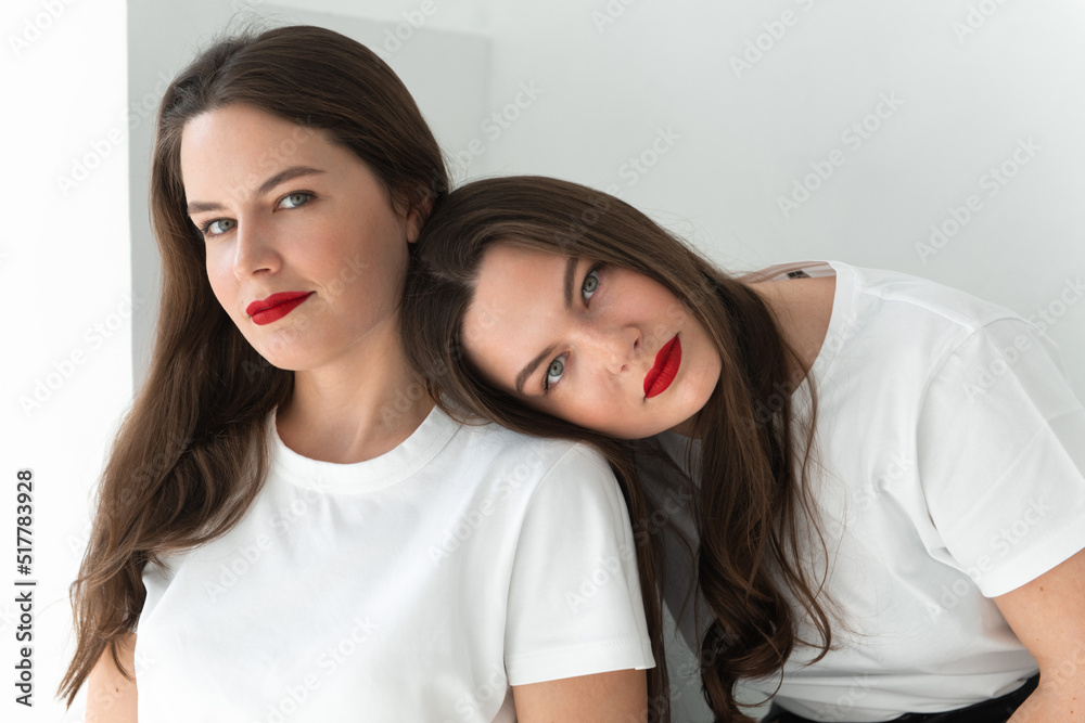 Two beautiful women twin sisters posing white background Two beautiful women twin sisters posing white background