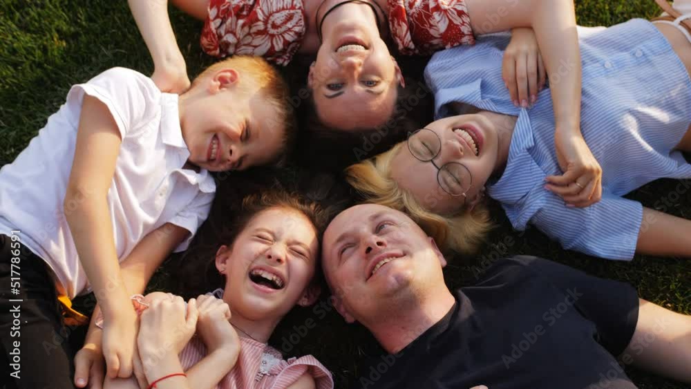 Happy modern family lying on ground and forming circle while looking up at camera, top view Happy modern family lying on ground and forming circle while looking up at camera, top view
