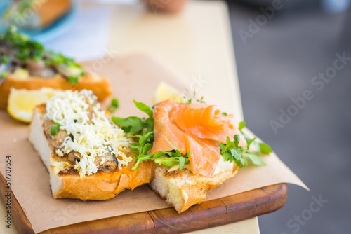 Sandwich with smoked salmon and salad. Bruschetta in fish restaurant. Seafood menu. Seafood canape. Dinner appetizer. Toast with fish and vegetables. Healthy lunch. Food close up. 