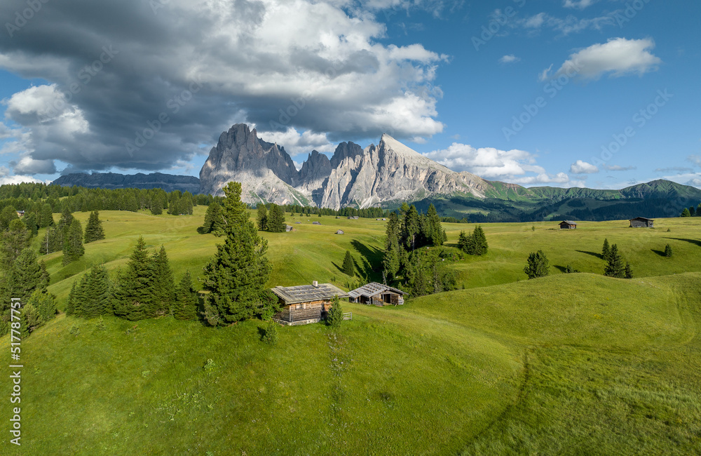 Aerial view of Seiser Alm valley with traditional wooden mountain huts in Dolomites Italy . Morning drone shot of idyllic Alpe di Suisi blooming meadow in South Tyrol 
