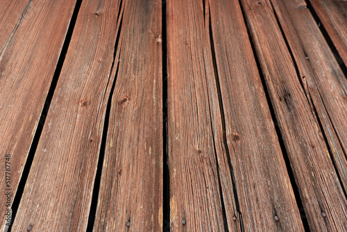 Close-up of a wall or floor made of old cracked planks. Remnants of brown paint and nail heads are visible. View from an angle. Background. Texture.