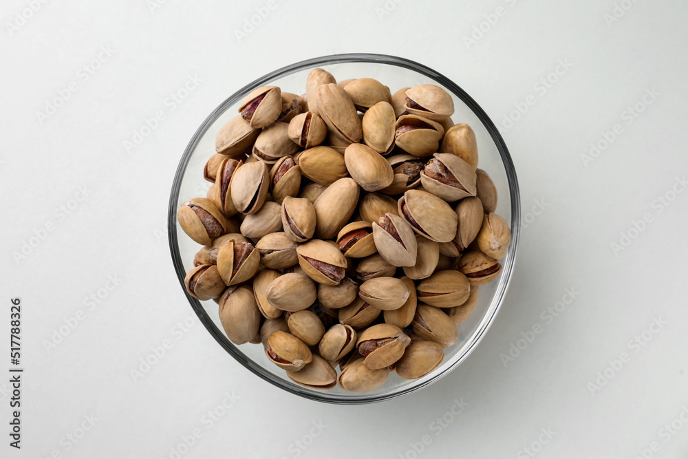 Bowl with pistachio nuts on white background, top view Bowl with pistachio nuts on white background, top view