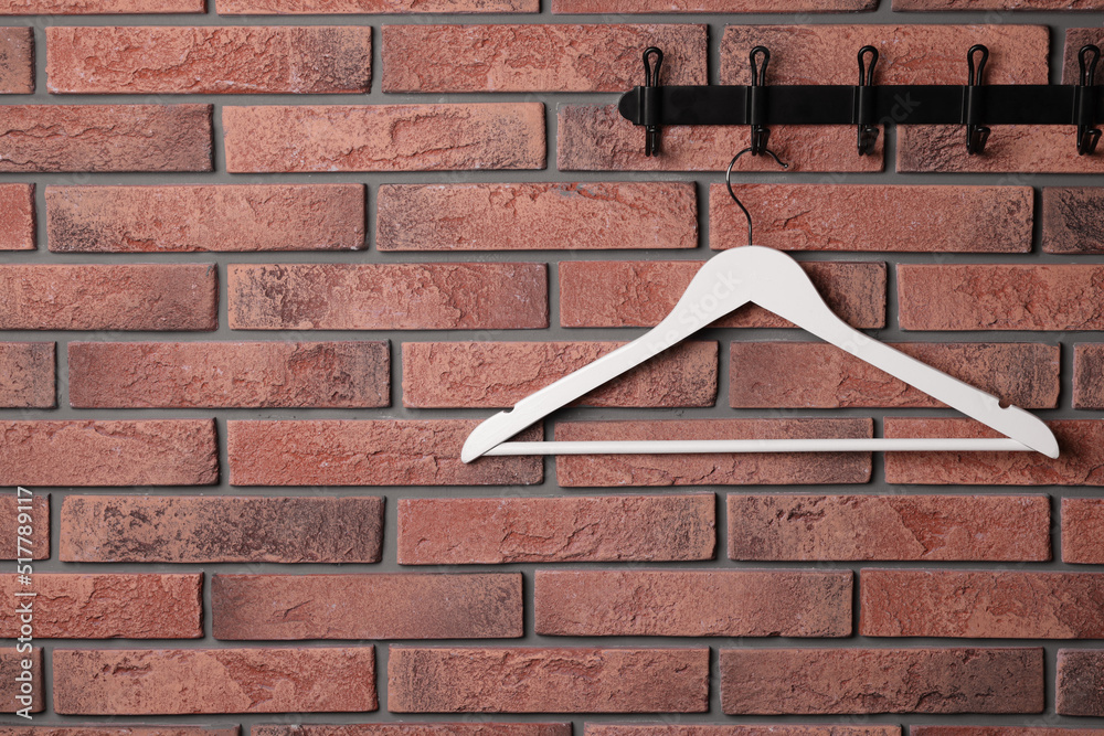 Hook rack with white clothes hanger on red brick wall. Space for text Stock  Photo