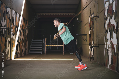 A middle aged athlete with a prosthetic leg training with a TRX.