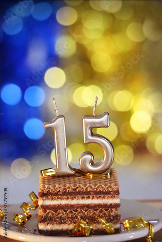 Birthday cake 15 with light gold candles.
Bright blue and yellow background. Vertical.