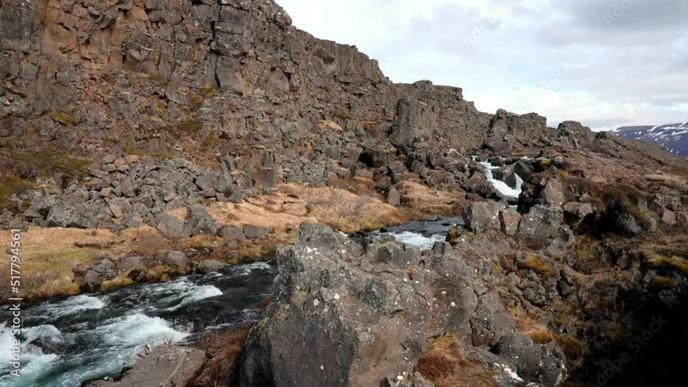 Tourists exploring rock formations in Iceland. Beautiful cliffs and deep fissure in Thingvellir National Park. Southern Iceland. Tourists exploring rock formations in Iceland. Beautiful cliffs and deep fissure in Thingvellir National Park. Southern Iceland.
