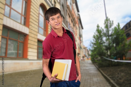 Portrait of happy teenager college or school boy with backpack holding books,