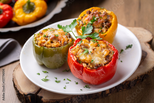 Foto Stuffed peppers, halves of peppers stuffed with rice, dried tomatoes, herbs and cheese in a baking dish on a blue wooden table, top view