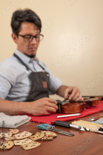 Tools to repair an instrument next to violin bridges on a workshop