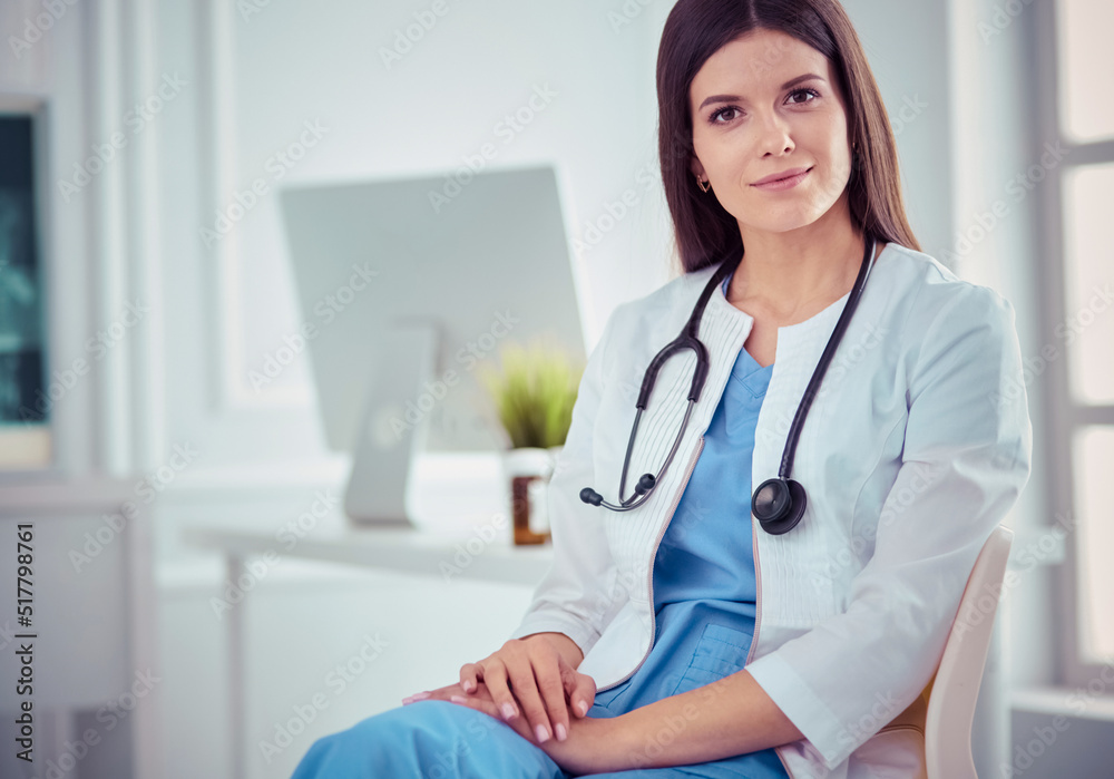 Beautiful female doctor sitting in a consulting room, smiling at the camera Beautiful female doctor sitting in a consulting room, smiling at the camera