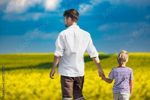 Young man taking his son for a walk out on an open field.