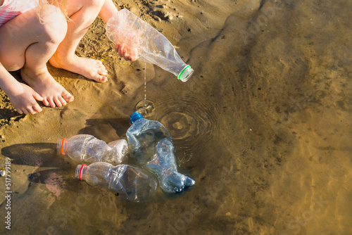 close-up of children's feet and plastic garbage on the beach or on the shore of a reservoir, the concept of cleaning the environment from the pollution of the planet