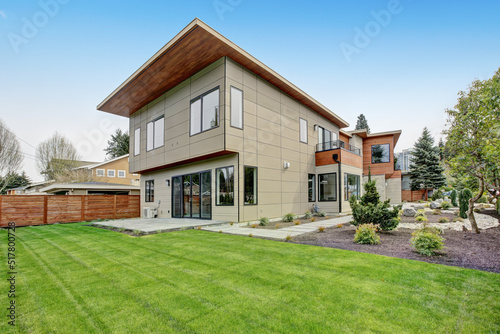 Contemporary style home luxury home exterior with brown walls and dark framed metal windows. Green Northwest landscaping. 