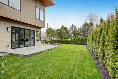 Contemporary style home luxury home exterior with brown walls and dark framed metal windows. Green Northwest landscaping. 