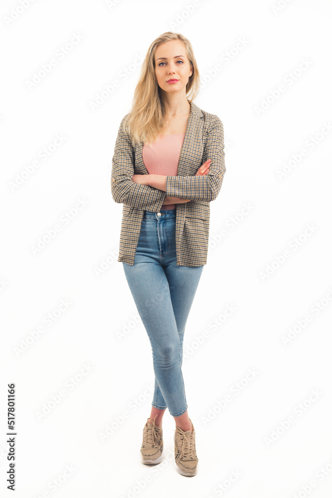 Beautiful young adult casually dressed caucasian woman looking at camera with serious facial expression and crossed legs and arms. Vertical studio shot. White background. Copy space. Full body. High Beautiful young adult casually dressed caucasian woman looking at camera with serious facial expression and crossed legs and arms. Vertical studio shot. White background. Copy space. Full body. High
