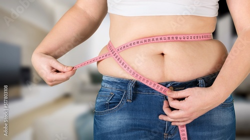 Φωτογραφία Woman standing showing excessive naked belly, measuring waist with hands, using tape